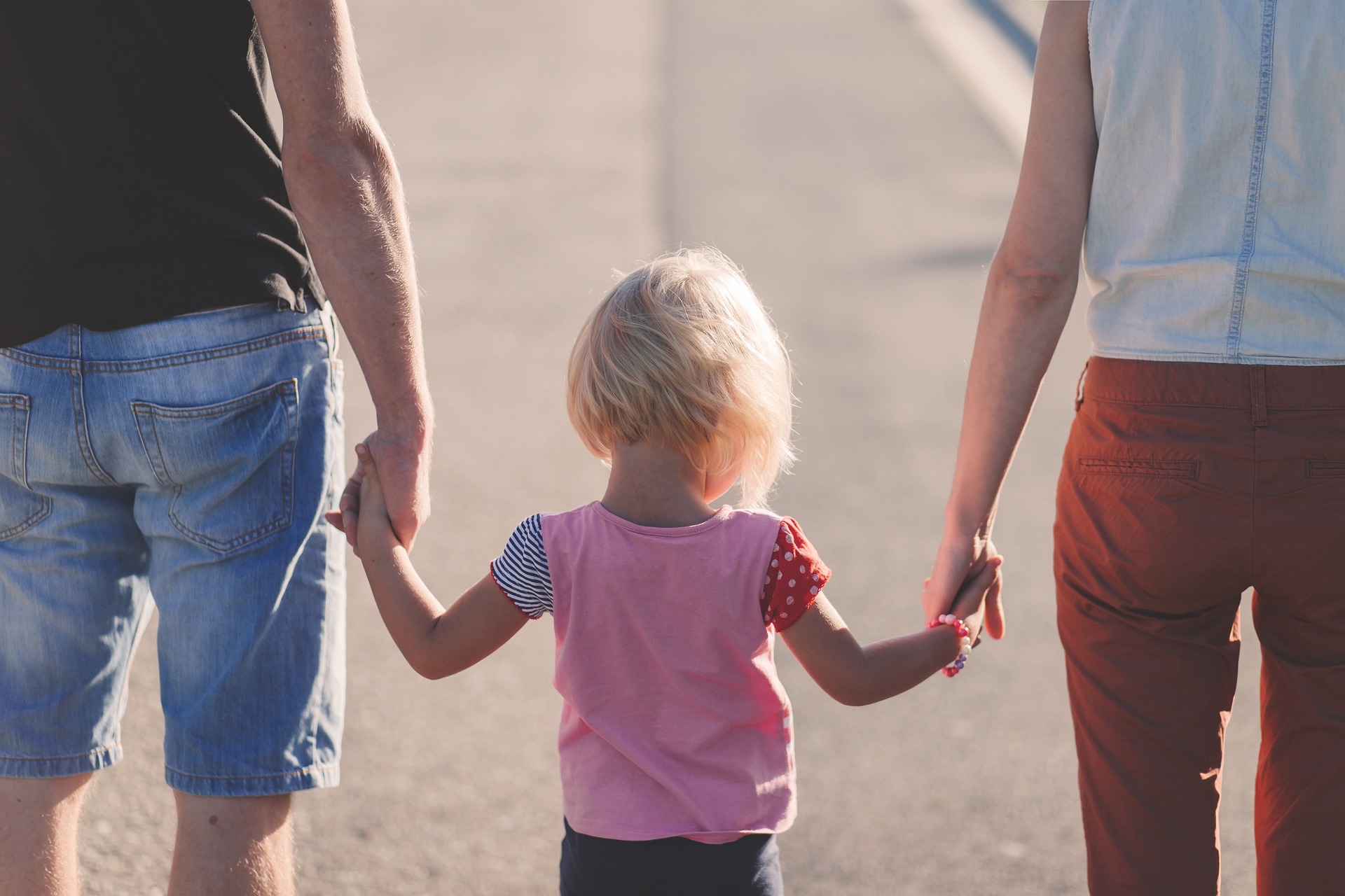 Des parents qui tiennent leur enfant par la main et marchent dans la rue