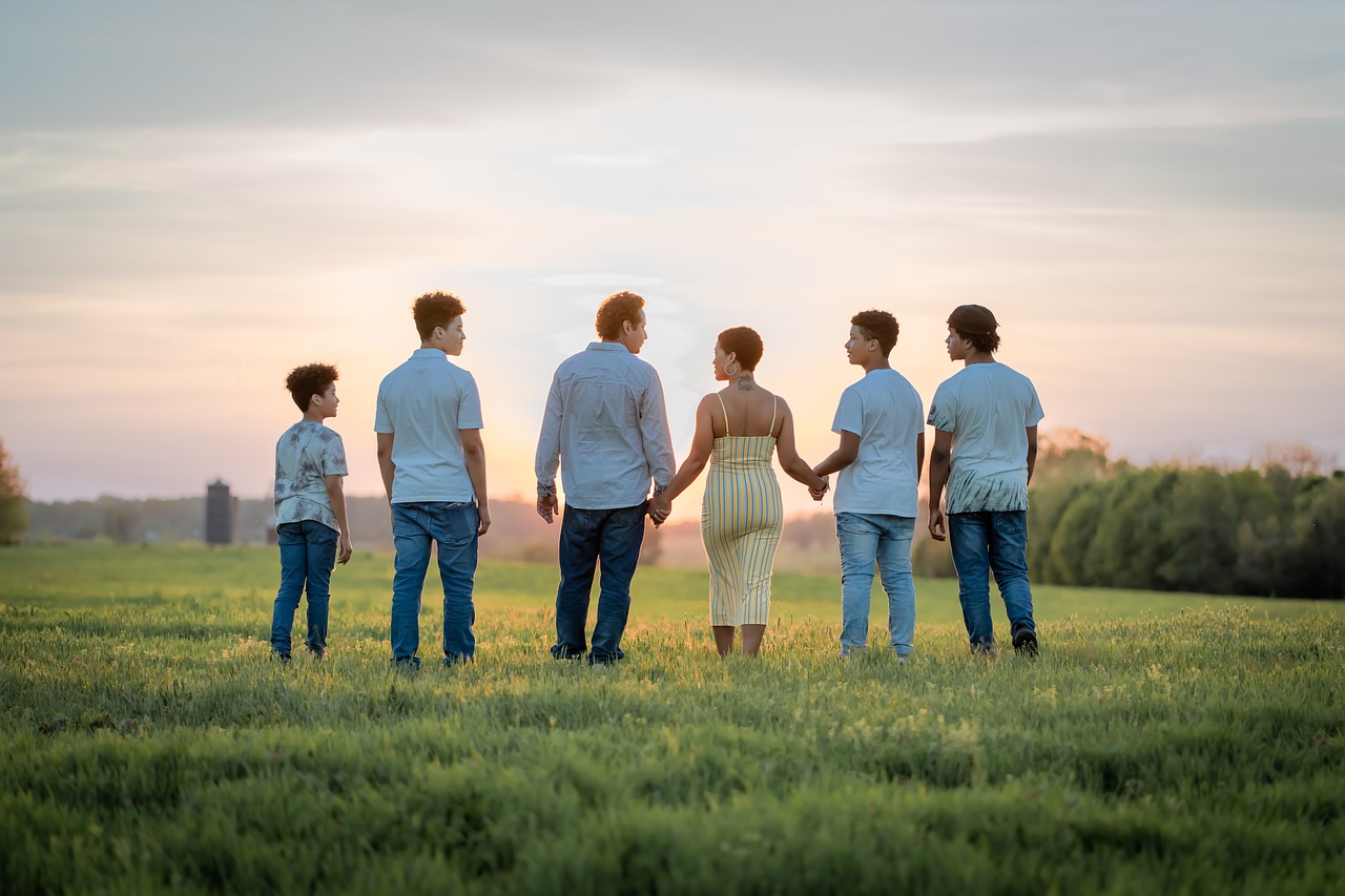 Un père, une mère et leurs 4 enfants qui marchent dans l'herbe, vus de dos
