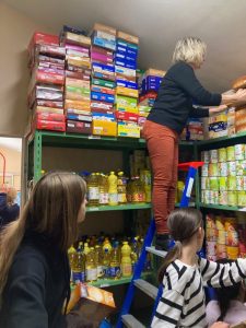 Des bénévoles rangent des denrées alimentaires dans une réserve.