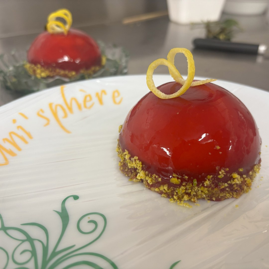 Une pâtisserie composée d'un entremet demi-sphérique posé sur un sablé