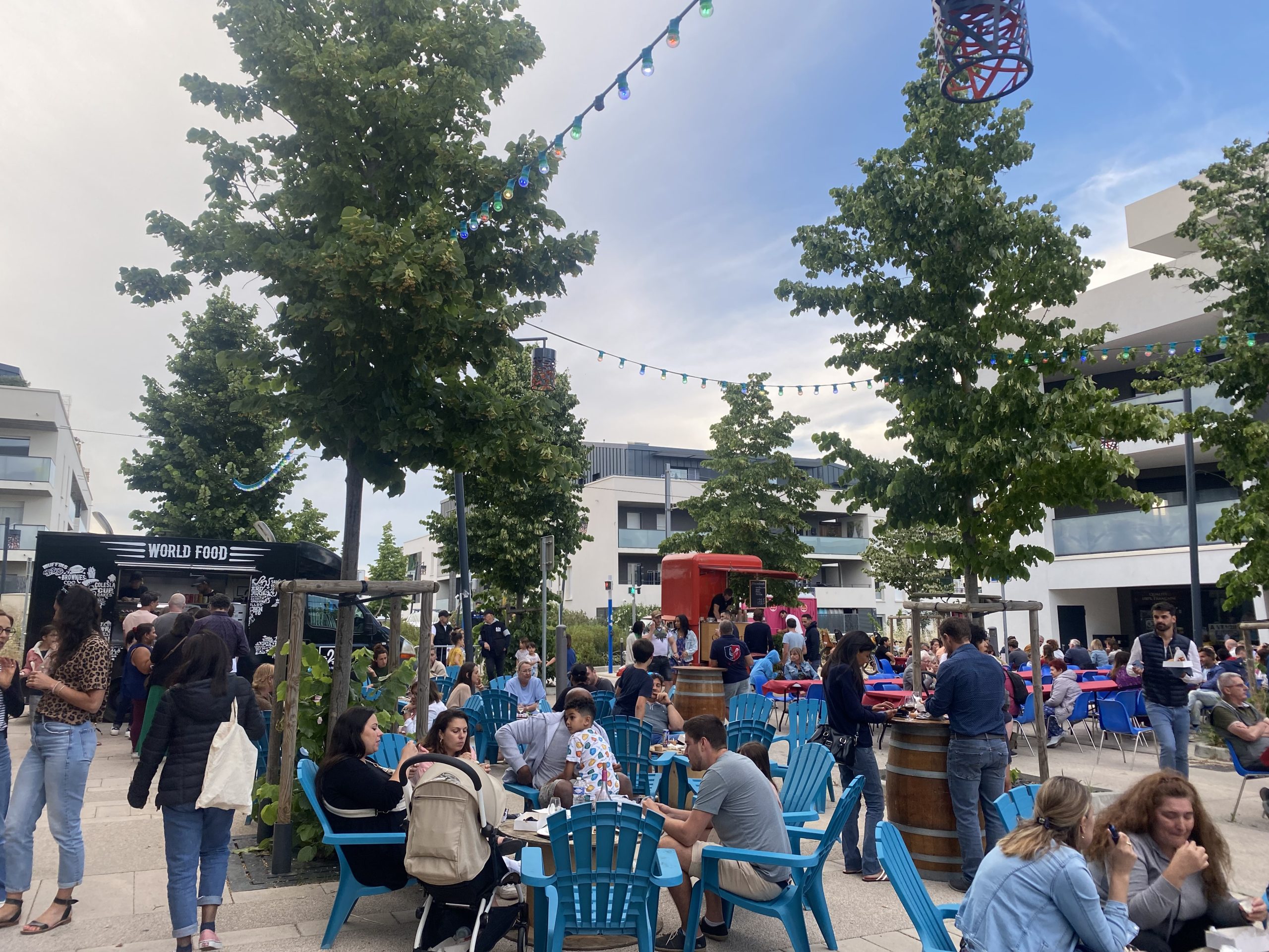 Des habitants réunis sur la place principale du quartier Caylus, décorée pour les Lez'tivales de Castelnau-le-Lez