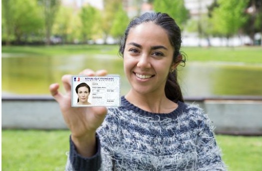 Une jeune femme montrant fièrement sa carte d'identité dans un parc