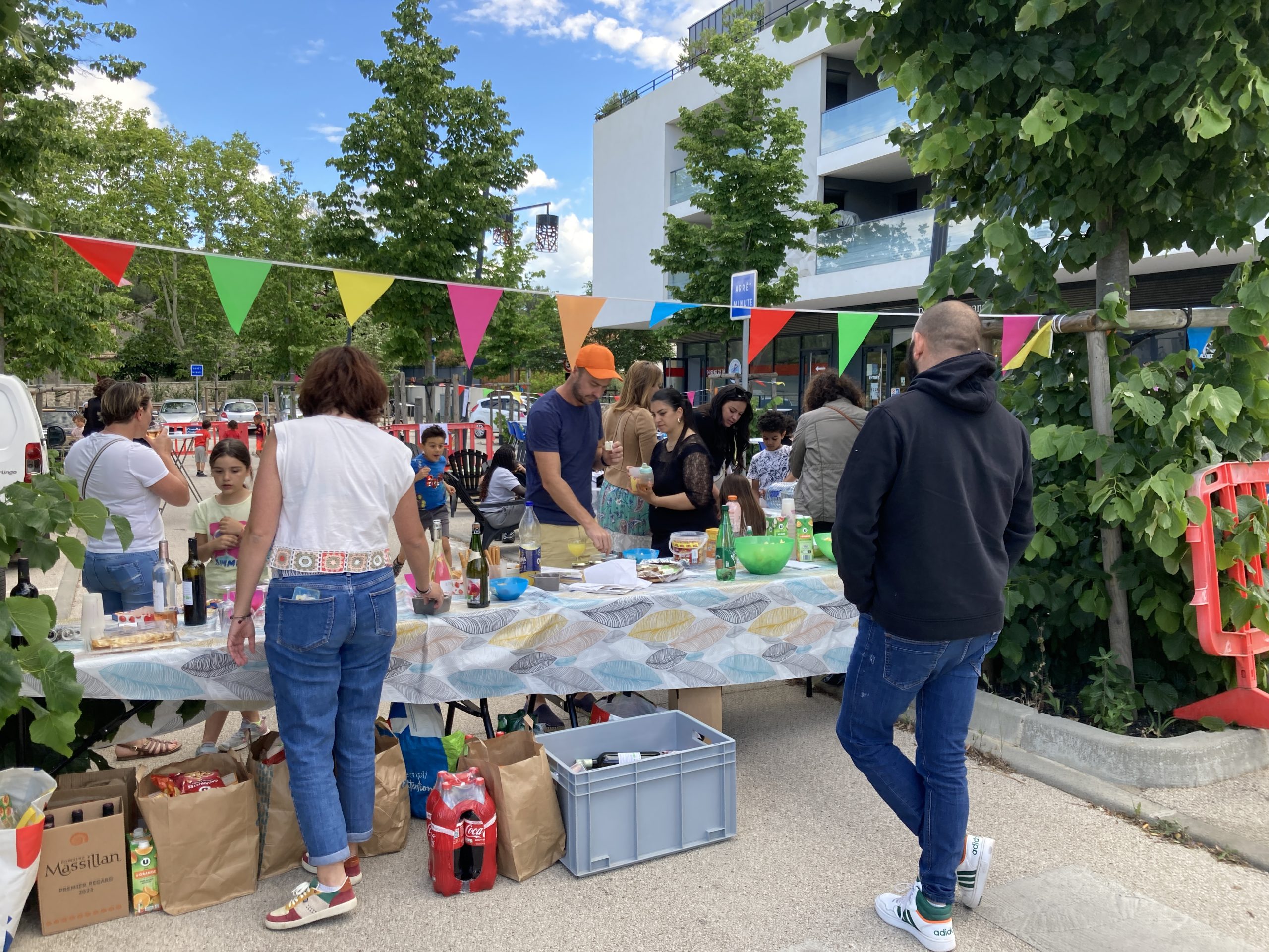 Des personnes réunies d'une table, des fanions multicolores au-dessus de leurs têtes