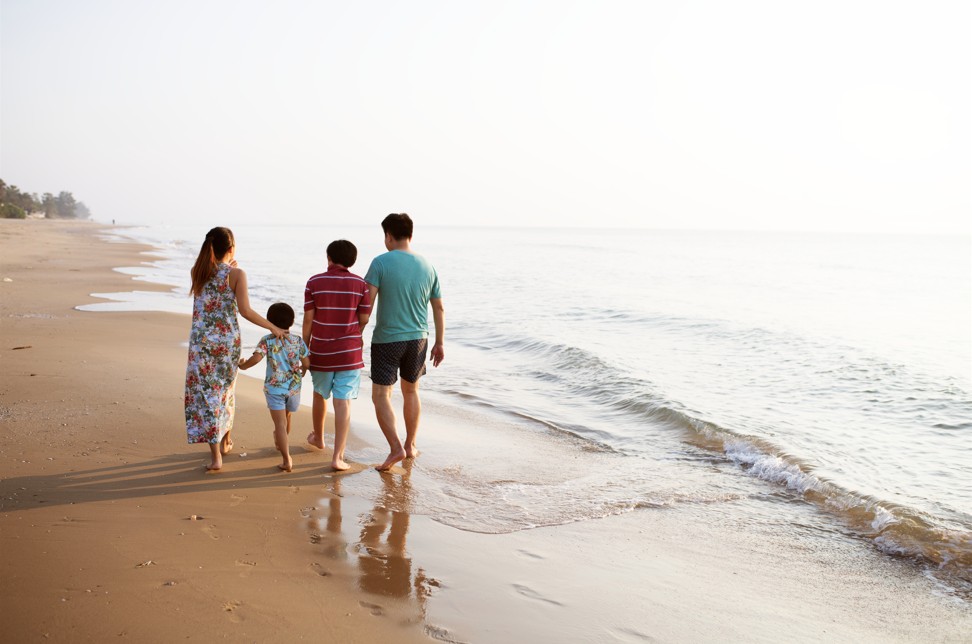 Une famille composée de 4 personnes vue de dos en train de sa promener en bord de mer
