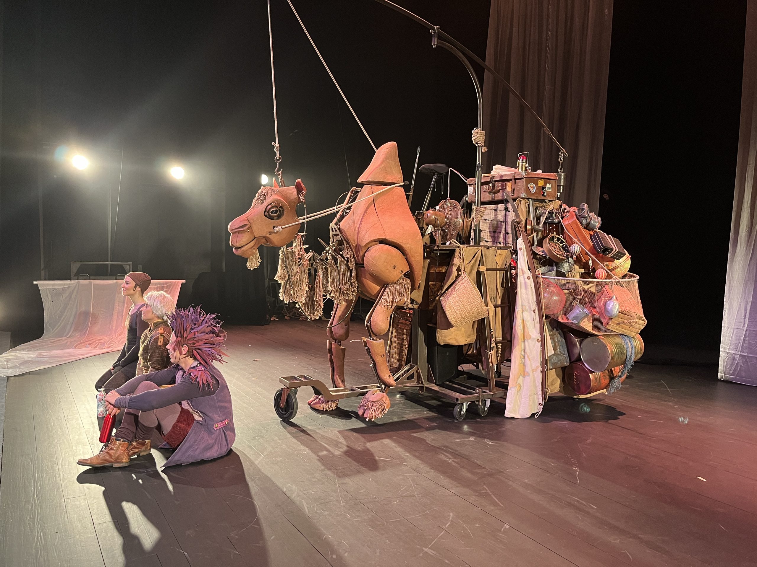 Les comédiens de "A dos de chameau" assis sur scène devant la marionnette monumentale en forme de chameau