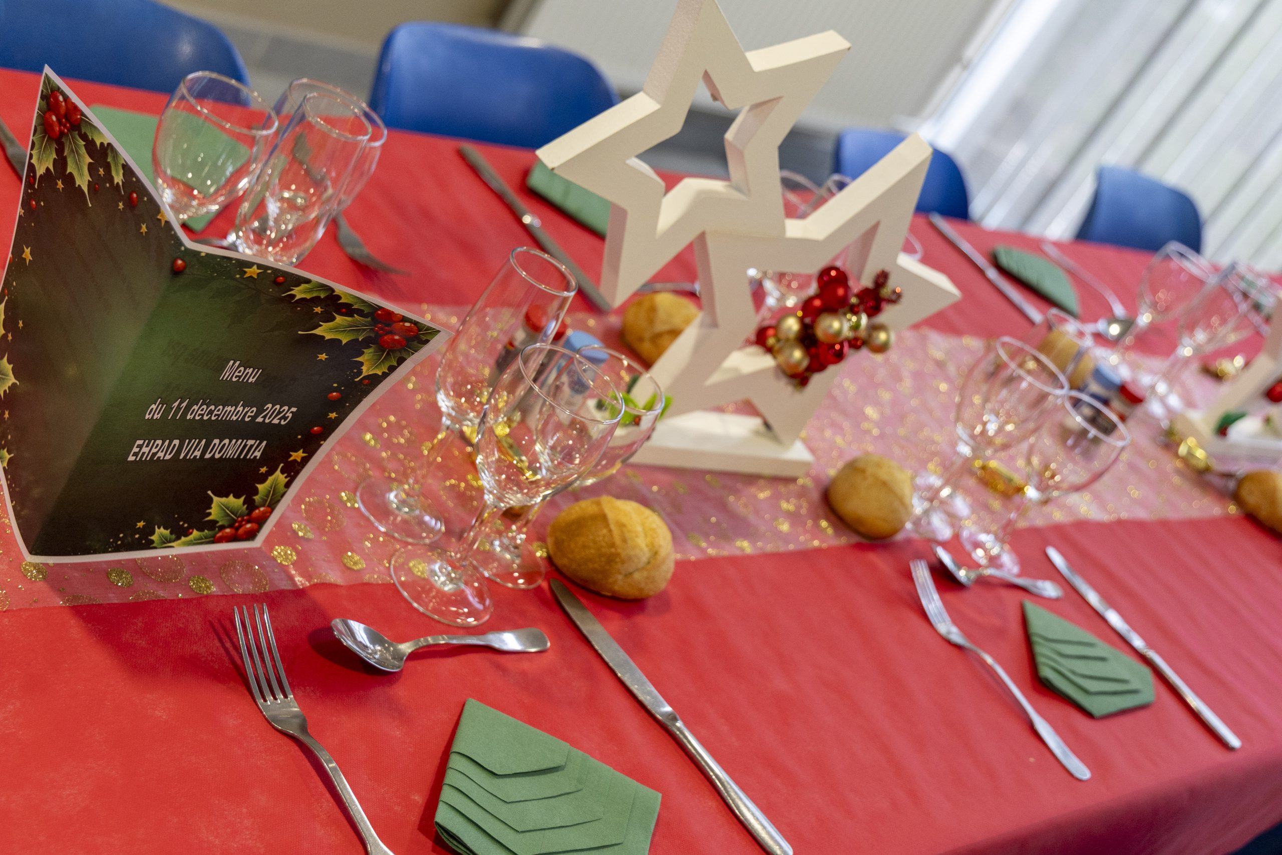Une table de fête avec une belle nappe rouge et des serviettes en papier de couleur verte pliées en forme de sapin de Noël