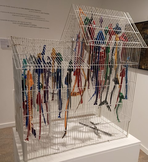 Une cage à oiseau dans laquelle pendent des arêtes de poissons peintes dans des couleurs vives