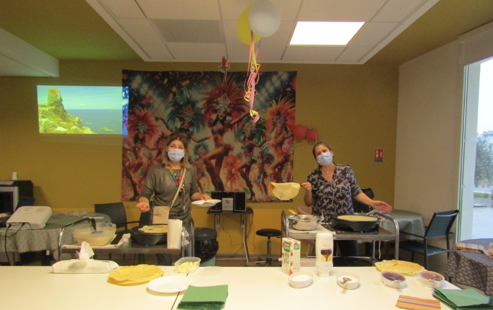 Deux femmes portant un masque, en train de faire des crêpes sur des crêpières électriques