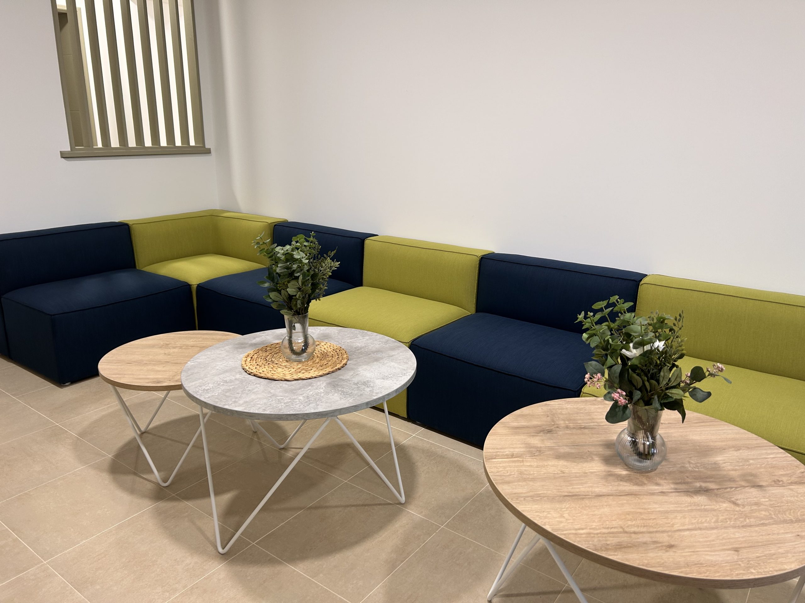 Le salon de la Maison d'Olympe, composé d'une alternance de fauteuil bleus et de fauteuils verts collés les uns aux autres pour former une banquette