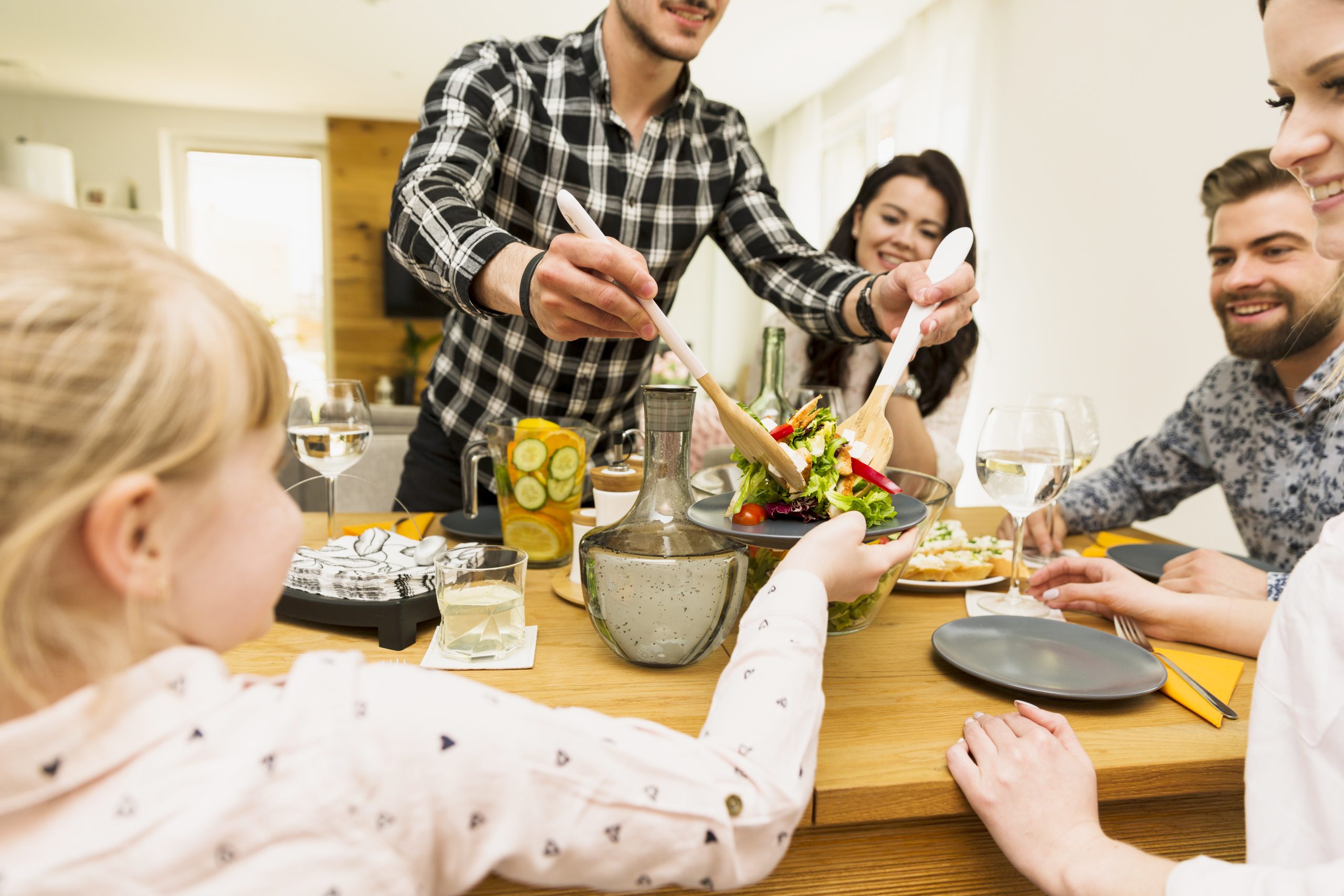 Une famille souriante, à table, prête à manger de la salade