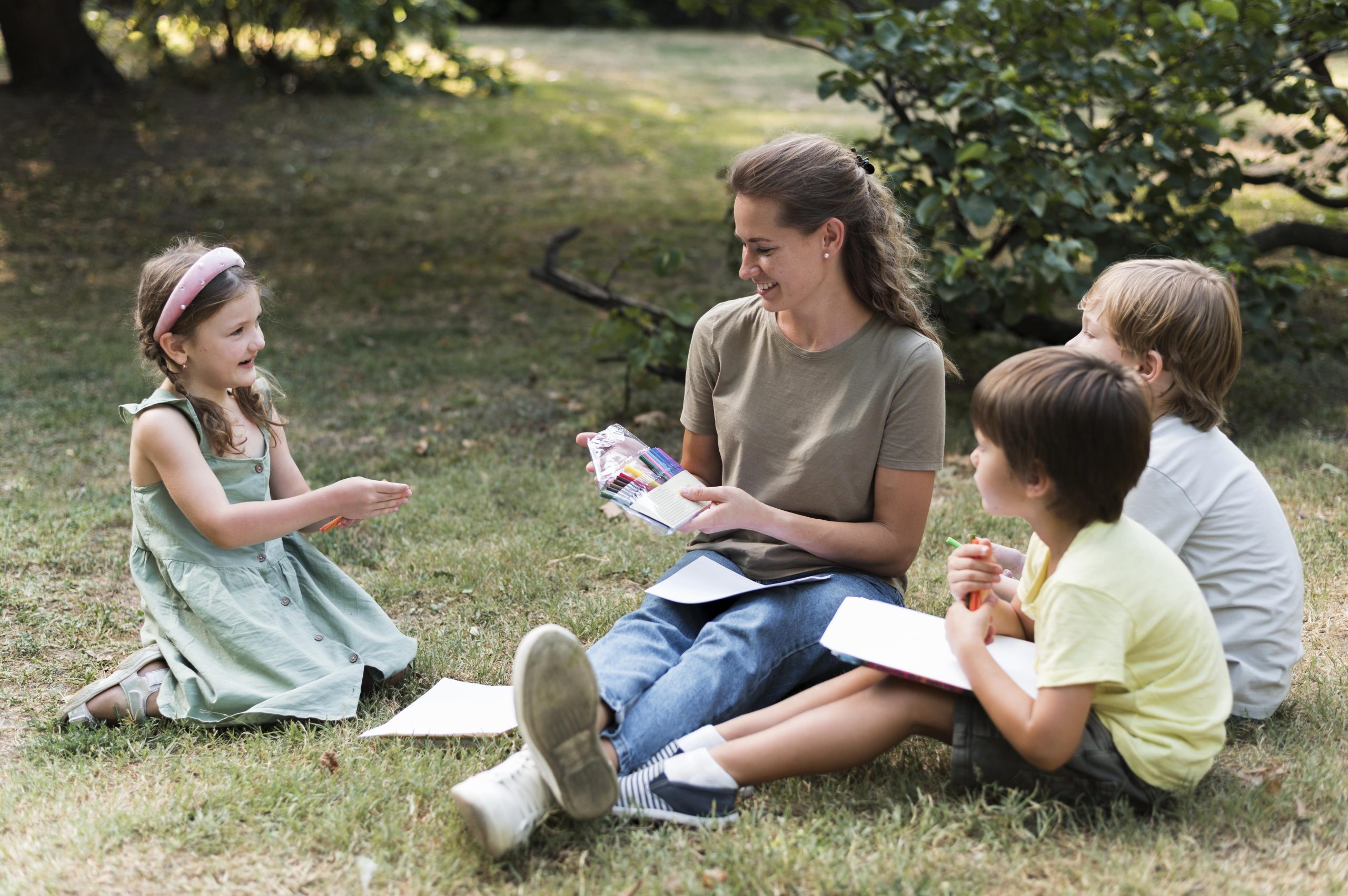 Une femme et des enfants assis dans un parc, elle leur lit des histoires